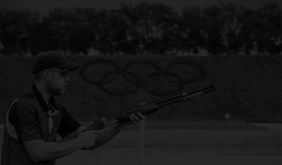 Wurfscheibenschütze Felix Haase mit seiner Perazzi vor den Olympischen Ringen