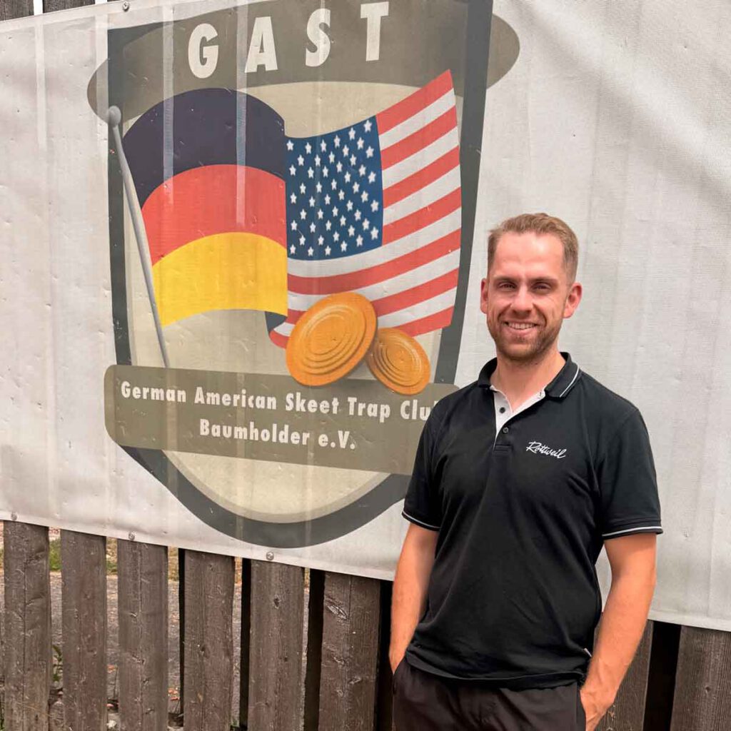 Felix Haase vor dem Eingangsbanner vom German American Skeet Trap Club Baumholder e.V.